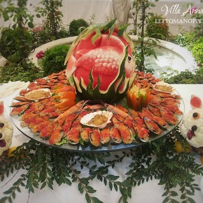 Buffet di crostacei e gamberi disposti a raggiera attorno a un'anguria intagliata a forma di pesce
