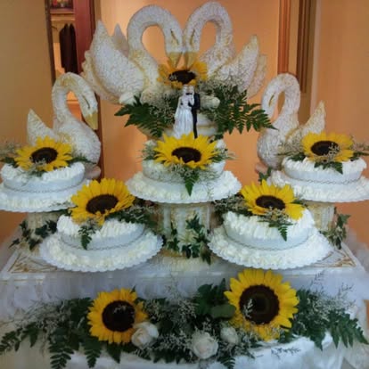 Composizione di torte nuziali con cigni e girasoli, con gli sposini in cima