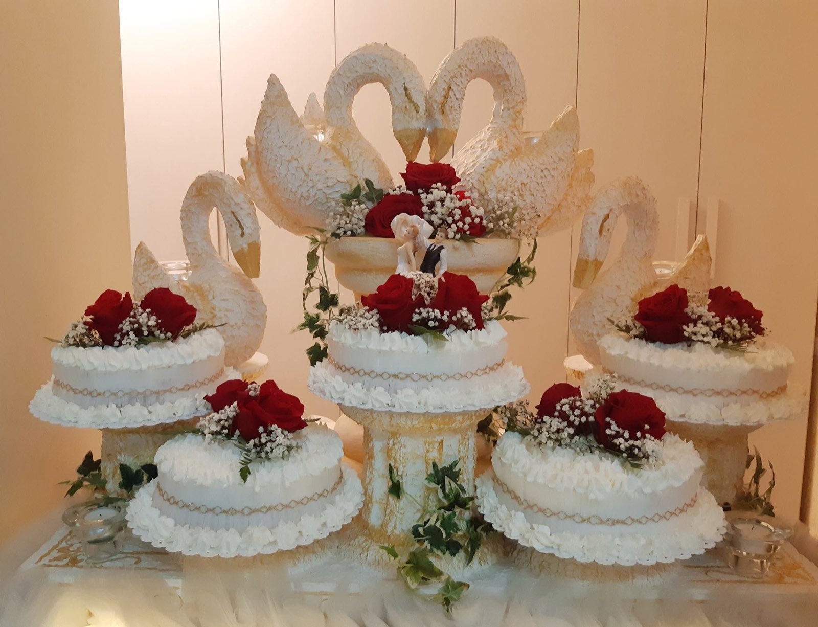 Composizione di torte nuziali con cigni decorati e rose rosse